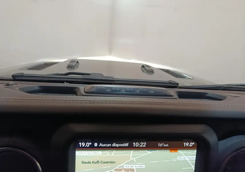 Vue intérieure centrée sur l'écran tactile de navigation du tableau de bord d'une Jeep Wrangler gris foncé.