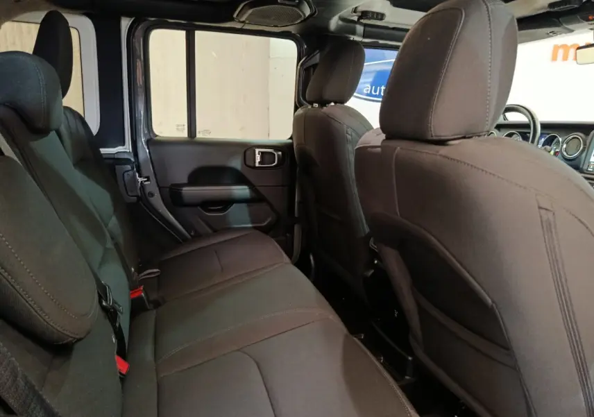 Vue intérieure arrière côté gauche du Jeep Wrangler 2022, sièges tissu gris foncé et espace arrière visible.