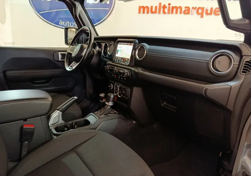 Vue intérieure côté conducteur du Jeep Wrangler 2022, tableau de bord noir avec écran tactile central et volant cuir multifonctions.