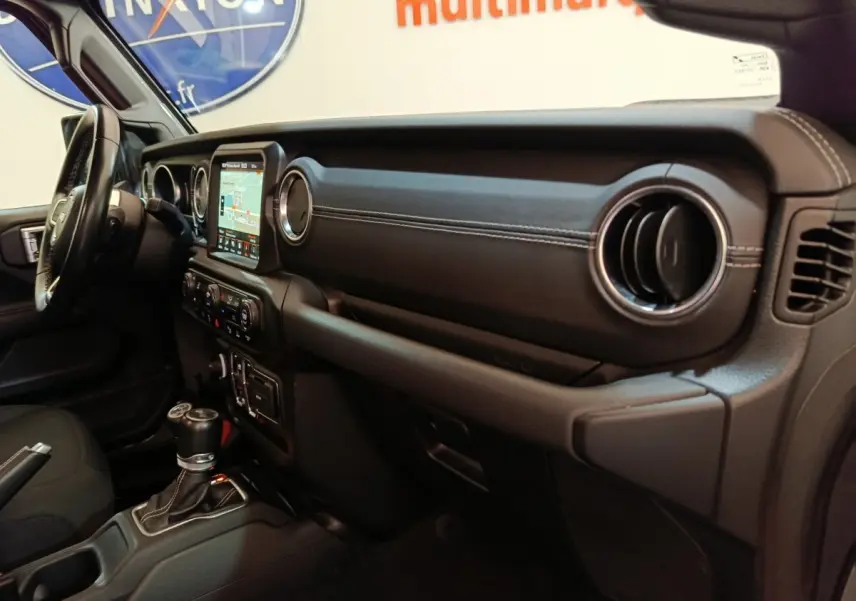 Vue intérieure côté passager du tableau de bord noir avec écran tactile et volant cuir de la Jeep Wrangler 2022.