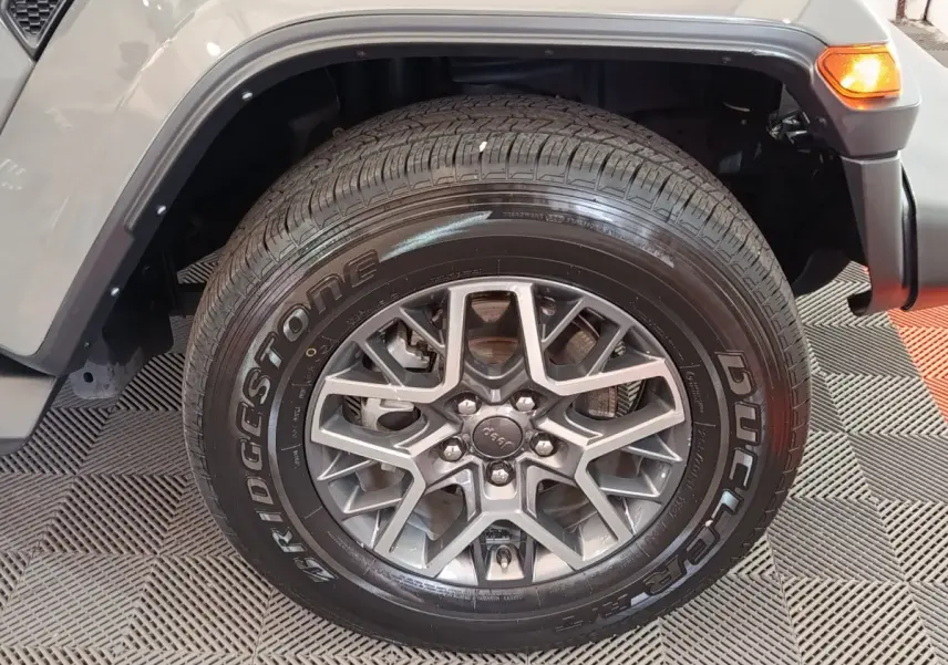 Gros plan sur la roue avant droite gris foncé du Jeep Wrangler 2022 avec jante aluminium et pneu Bridgestone.