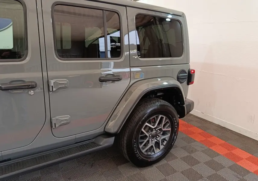 Vue latérale droite sur l’arrière d’un Jeep Wrangler 2022 gris foncé avec jante aluminium et porte essence visible.