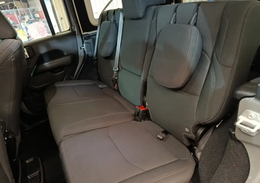 Vue latérale droite sur la banquette arrière noire du Jeep Wrangler Sahara 2022, avec appuie-têtes et ceintures visibles.