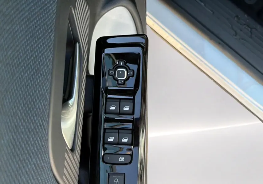 Gros plan sur la commande des vitres électriques côté conducteur du Citroën C5 Aircross blanc et noir, porte ouverte.