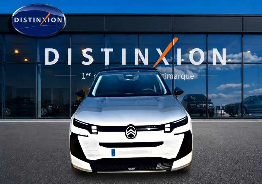 Vue de face du Citroën C5 Aircross blanc et noir avec calandre moderne et logo centré devant un bâtiment vitré.