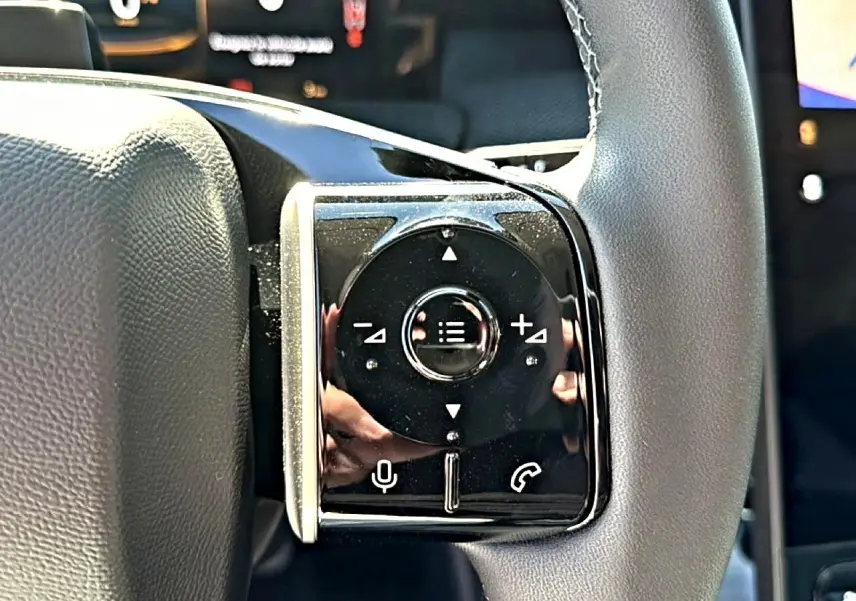 Gros plan sur les commandes multifonctions noires à gauche du volant gris du Citroën C5 Aircross hybride 2026.