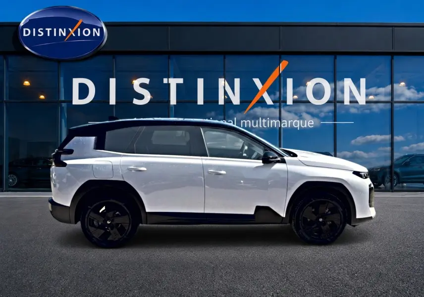 Profil droit du Citroën C5 Aircross hybride blanc avec toit noir, jantes alliage noires, devant une vitrine Distinxion.