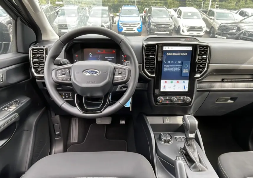 Intérieur du Ford Ranger 2025 gris carbone, vue frontale sur le volant, tableau de bord numérique et écran tactile central.