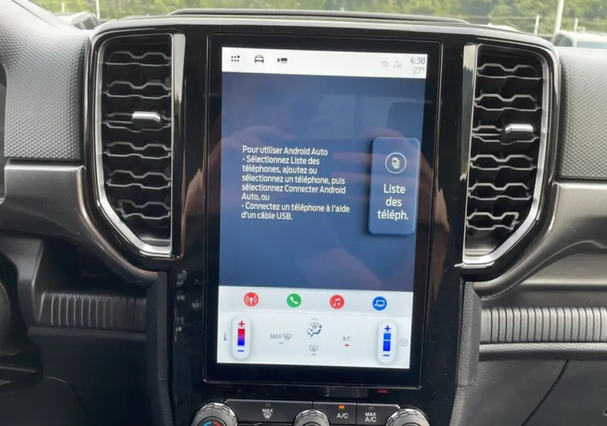 Écran tactile central du Ford Ranger 2025 gris carbone, vue rapprochée du tableau de bord avec commandes climatisation visibles.
