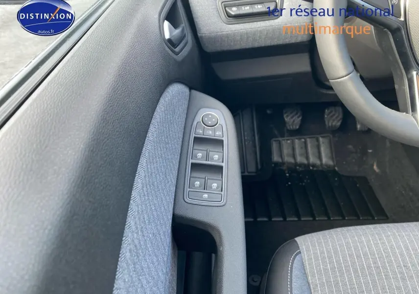 Vue intérieure côté conducteur de la Renault Clio V 2025, montrant la porte avec commandes des vitres et pédalier.