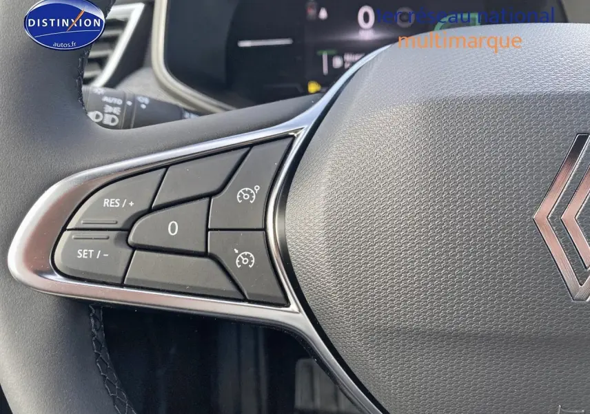 Gros plan sur le volant multifonction gris avec commandes de régulateur de vitesse de la Renault Clio V.