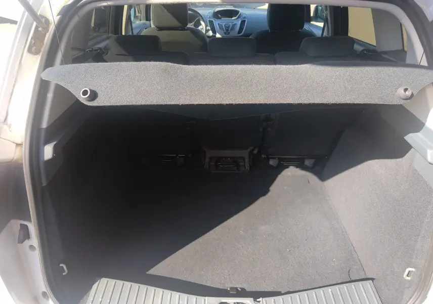 Vue arrière du coffre ouvert d'une Ford C-MAX blanche de 2013, montrant l'intérieur spacieux et la tablette cache-bagages relevée.