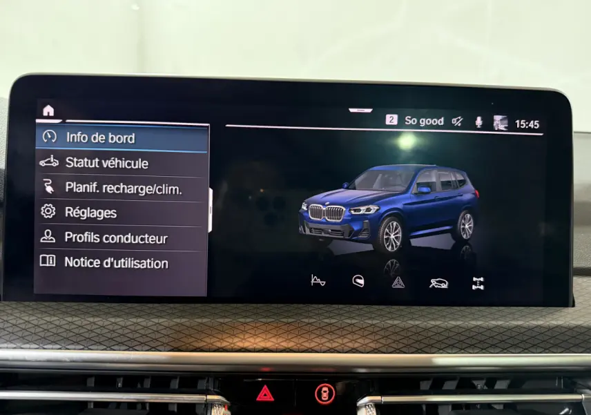 Écran tactile intérieur affichant un BMW X3 bleu en vue 3/4 avant avec menu de bord à gauche.