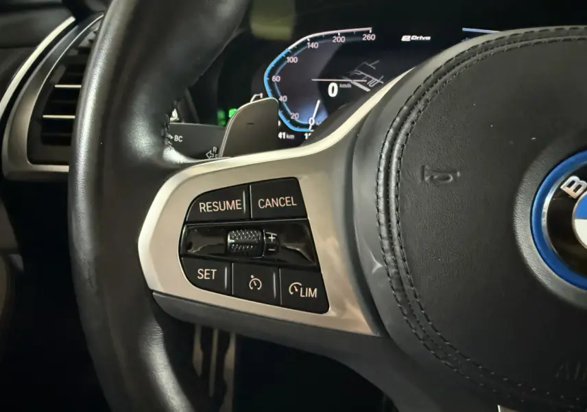 Gros plan sur le côté gauche du volant cuir de la BMW X3 xDrive30e 2023 avec commandes de régulateur de vitesse.