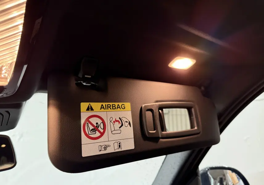 Détail du pare-soleil côté conducteur avec miroir et avertissement airbag, intérieur noir du BMW X3 xDrive30e 2023.