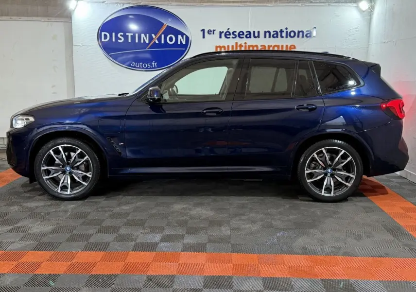 Vue de profil côté gauche d'un BMW X3 xDrive30e bleu foncé avec jantes alliage et vitres teintées.