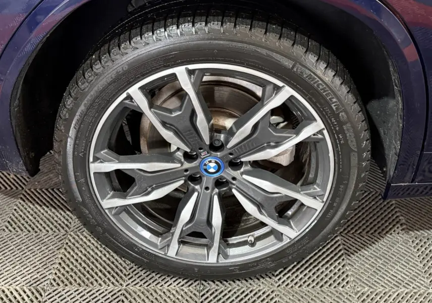 Gros plan sur la roue avant droite d’un BMW X3 bleu 2023 avec jante alliage M Sport à design complexe.