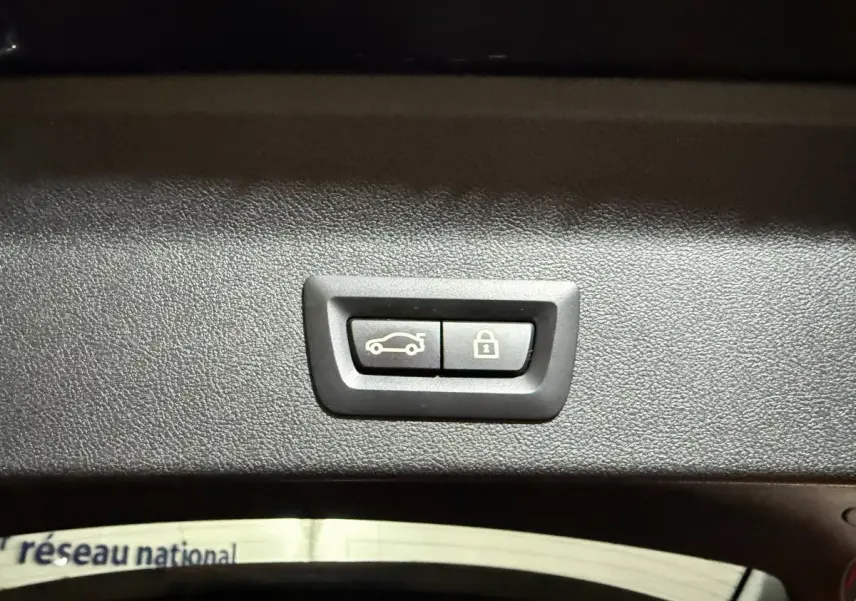 Boutons d'ouverture et de verrouillage du coffre sur le panneau intérieur du BMW X3 bleu hybride rechargeable.