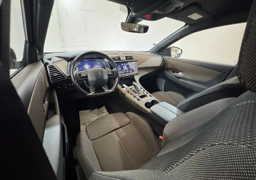 Intérieur du DS7 Crossback vu côté conducteur, tableau de bord moderne avec écran tactile et volant multifonctions noir.