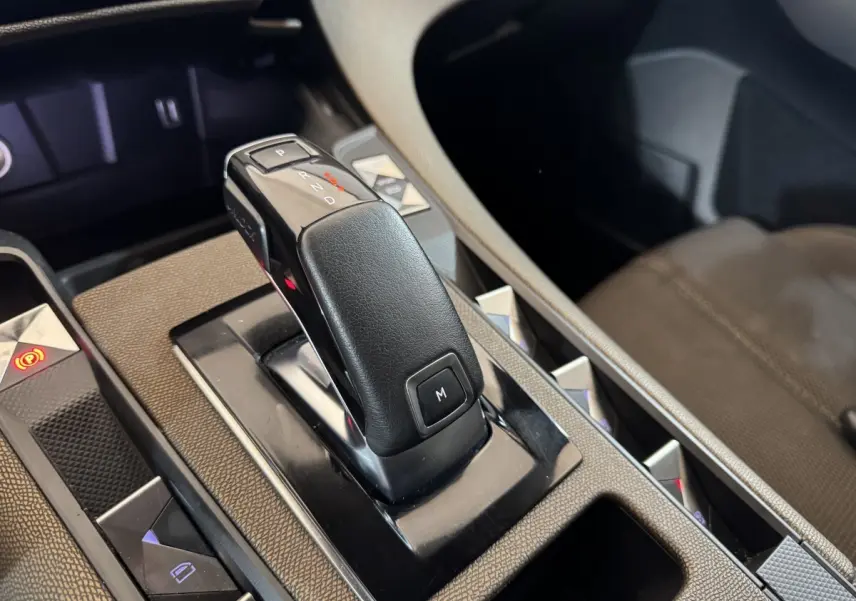 Gros plan sur la commande de boîte automatique noire du DS7 Crossback gris foncé, avec détails de la console centrale.