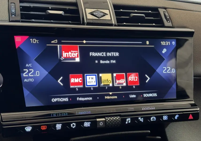 Écran tactile central du tableau de bord du DS7 Crossback 2020 affichant les stations radio, avec commandes climatisation en dessous.