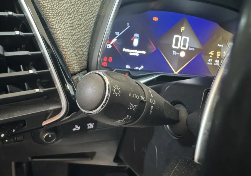 Gros plan sur la commande des phares et le tableau de bord numérique du DS7 Crossback gris foncé, affichage 12 pouces.