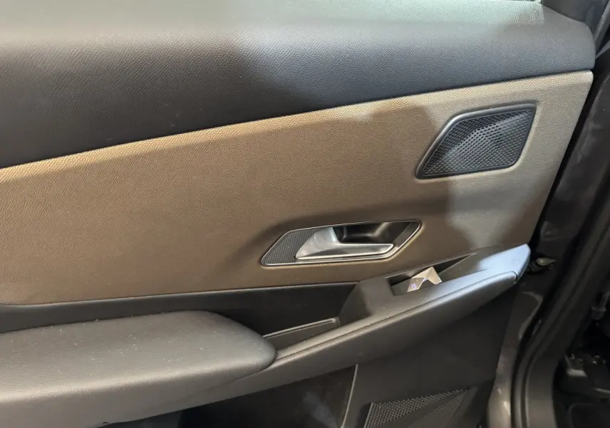 Détail de la porte intérieure côté gauche du DS7 Crossback gris foncé, avec poignée argentée et haut-parleur intégré.