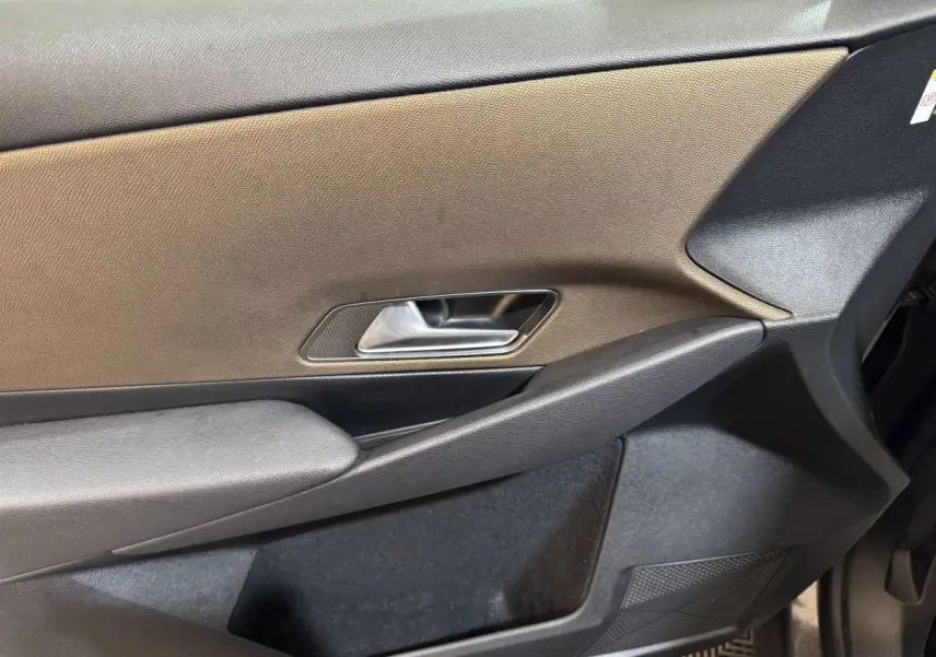 Vue rapprochée de la porte avant gauche du DS7 Crossback gris foncé, montrant la poignée intérieure et le panneau en tissu.