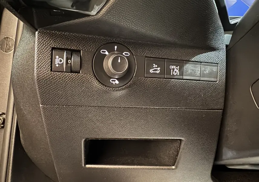 Gros plan sur les commandes noires côté gauche du tableau de bord du DS7 Crossback gris foncé, avec réglage phares et ouverture coffre.