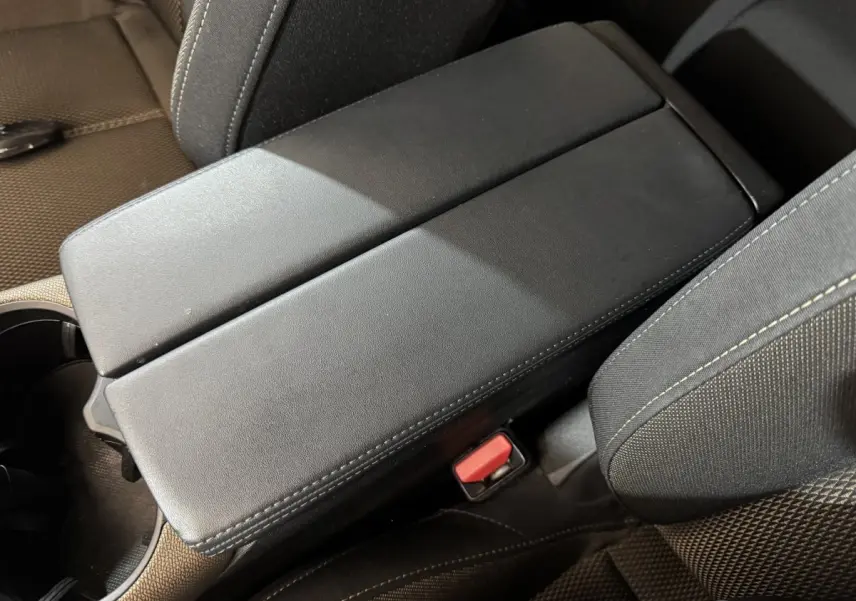 Gros plan sur l'accoudoir central noir et les sièges en tissu gris foncé du DS7 Crossback PureTech 130 Business.