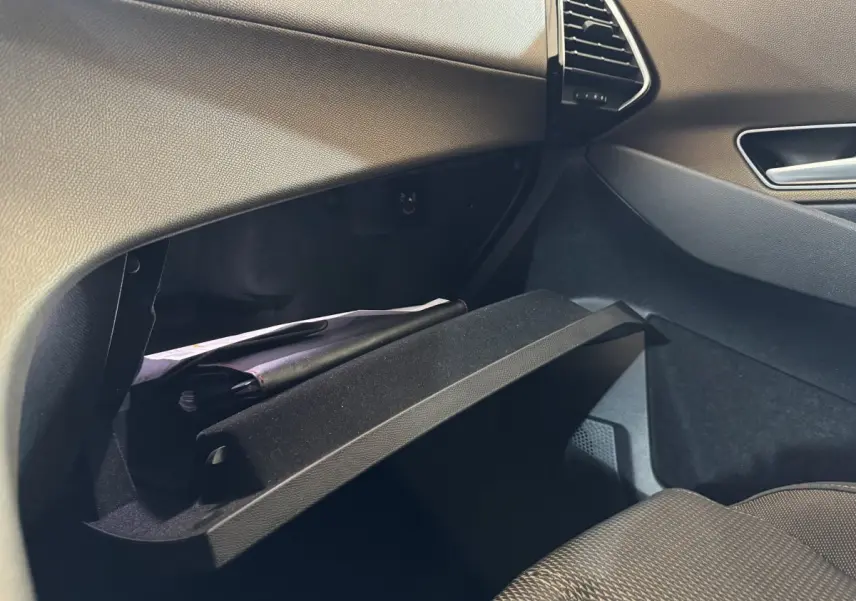 Vue intérieure côté passager du coffre à gants ouvert du DS7 Crossback gris foncé, montrant des documents à l'intérieur.