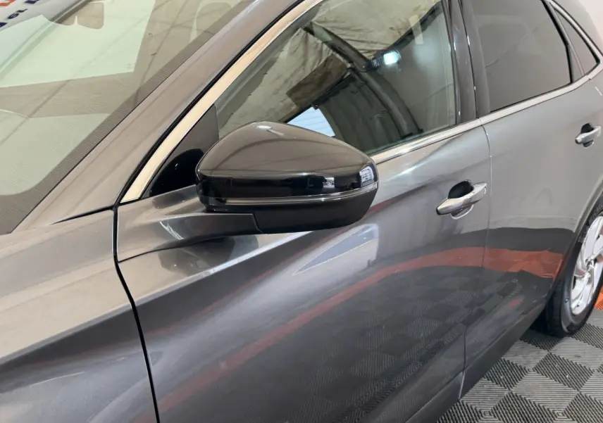 Vue latérale gauche rapprochée du DS7 Crossback gris foncé, mettant en valeur le rétroviseur noir brillant et les poignées de porte chromées.