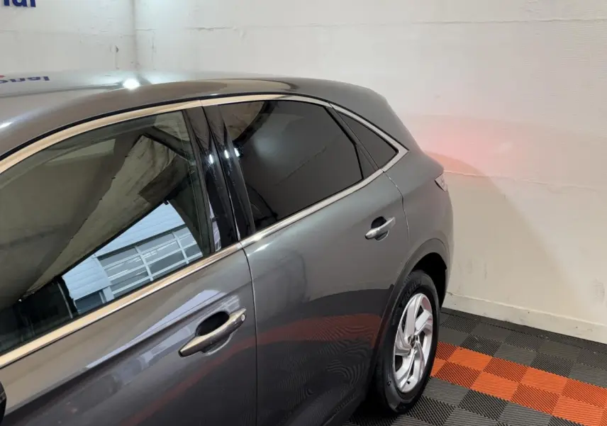 Vue côté droit arrière du DS7 Crossback gris foncé, mettant en valeur les vitres teintées et les jantes argentées.
