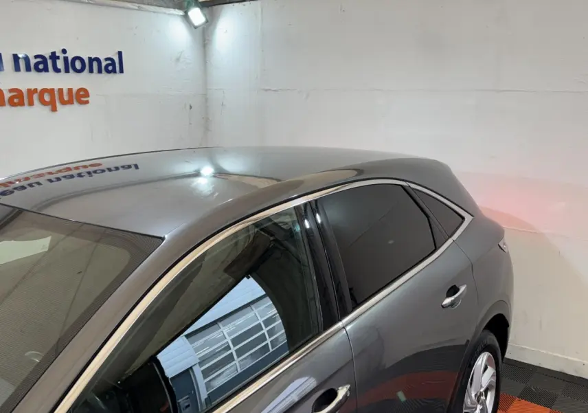 Vue 3/4 arrière côté gauche d'un DS7 Crossback gris foncé avec vitres teintées dans un garage.