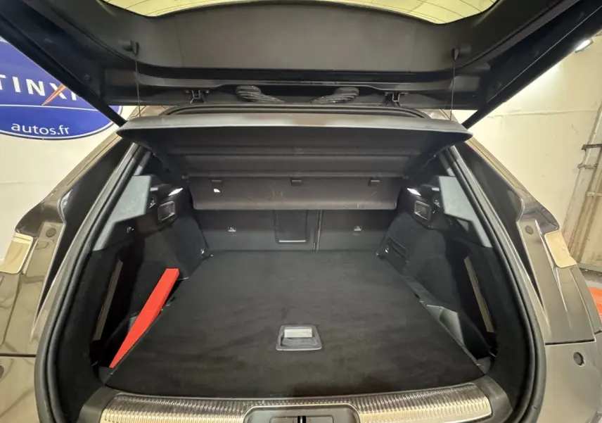 Vue arrière du coffre ouvert d'un DS7 Crossback gris foncé, montrant un espace de chargement spacieux et bien fini.