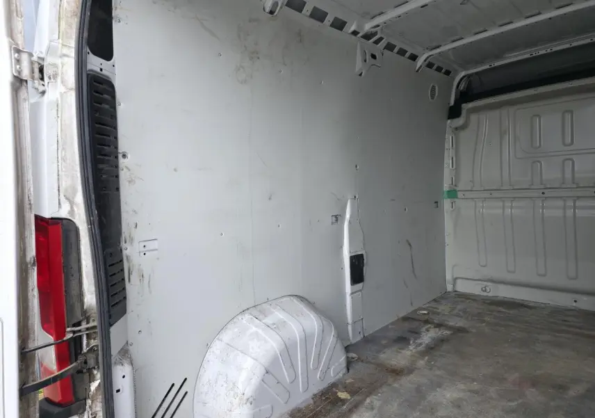 Vue intérieure de la cellule de chargement blanche du Peugeot Boxer Fourgon, montrant la cloison et le plancher usé.