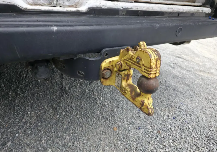 Gros plan sur le crochet d'attelage jaune rouillé fixé à l'arrière d'un Peugeot Boxer Fourgon blanc.