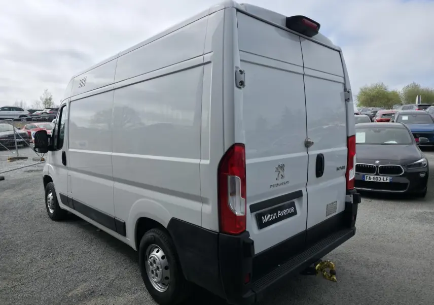 Vue 3/4 arrière droite du Peugeot Boxer Fourgon blanc avec crochet d'attelage et portes arrière battantes fermées.