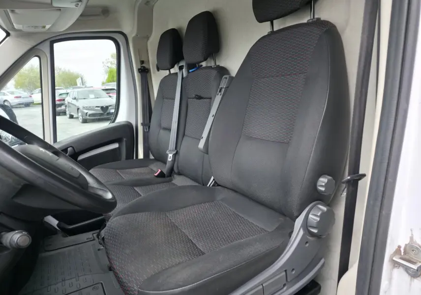 Vue intérieure côté conducteur du Peugeot Boxer Fourgon blanc 2022, montrant les sièges tissu Darko et le volant.