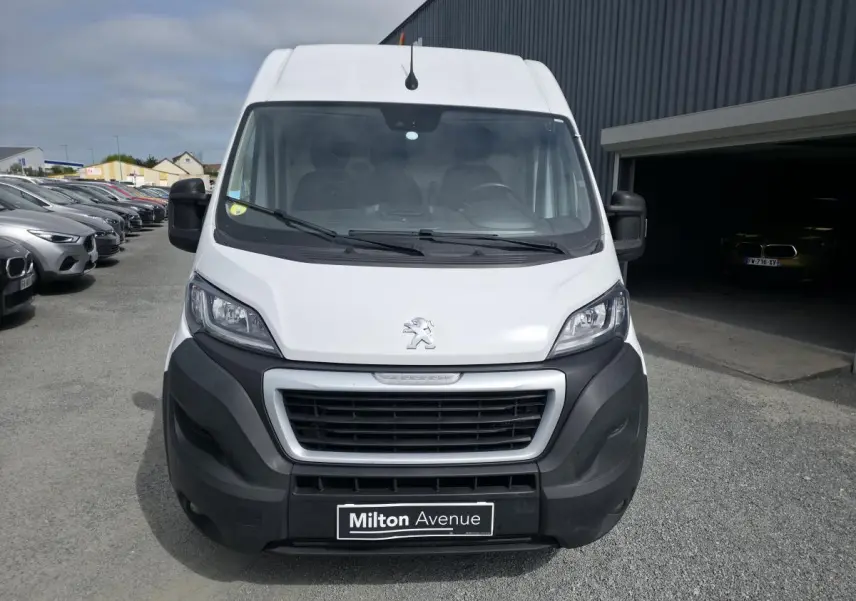 Vue avant d'un Peugeot Boxer Fourgon blanc avec pare-chocs noirs et calandre imposante sur parking.
