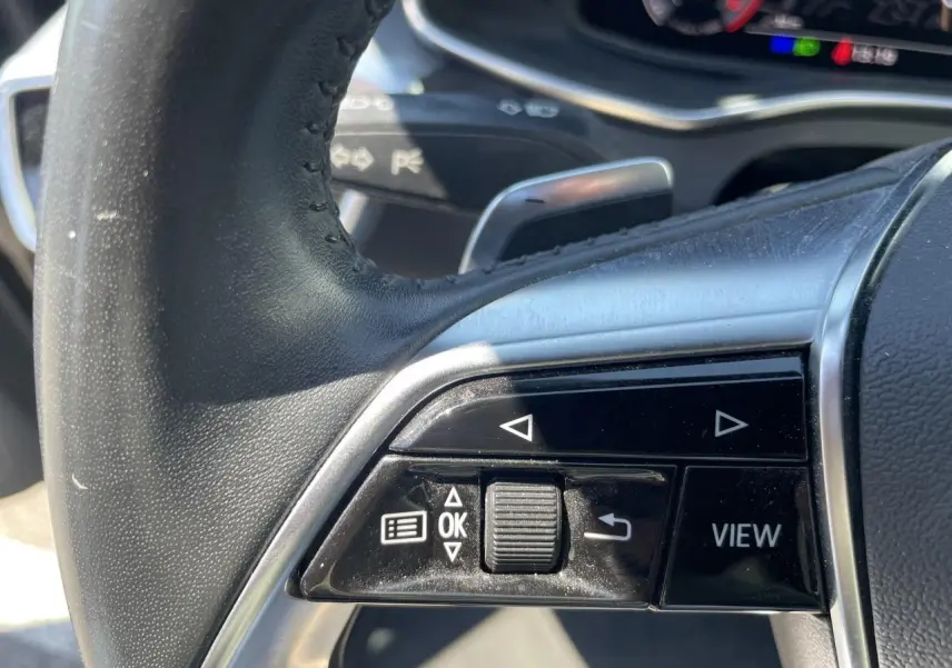 Gros plan sur les commandes gauche du volant en cuir noir de l'Audi A6 V Avant 45 TDI 2019.