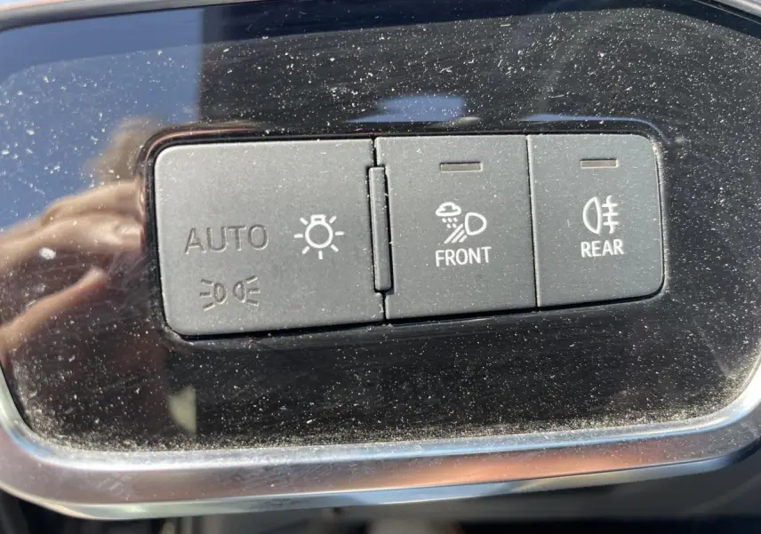 Gros plan sur les boutons de commande d’éclairage automatique et antibrouillard avant/arrière sur tableau de bord noir brillant.