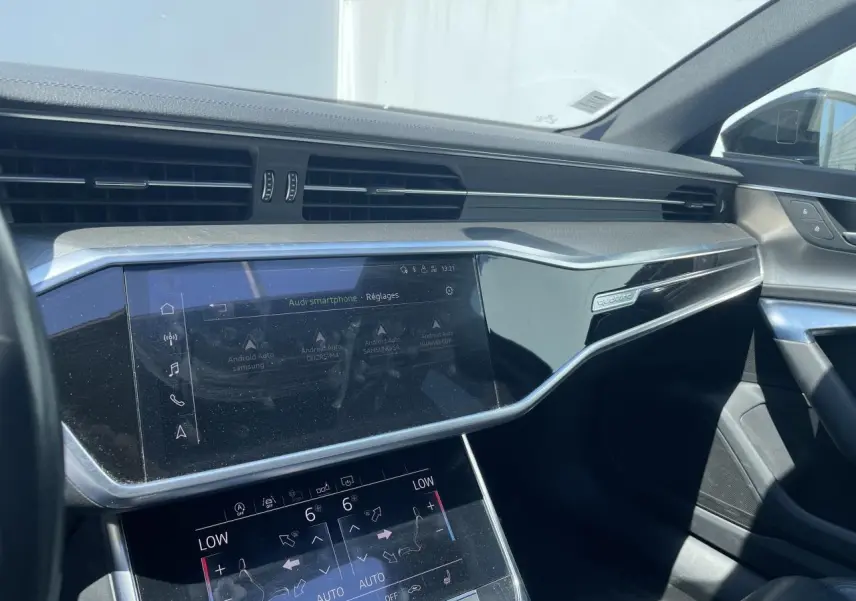 Vue intérieure côté passager de l'Audi A6 2019 noire, mettant en valeur le tableau de bord et l'écran tactile central.