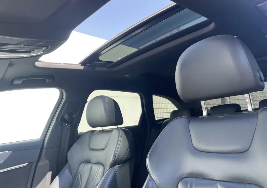 Intérieur noir cuir de l'Audi A6 2019, vue rapprochée des sièges avant avec toit panoramique ouvert.