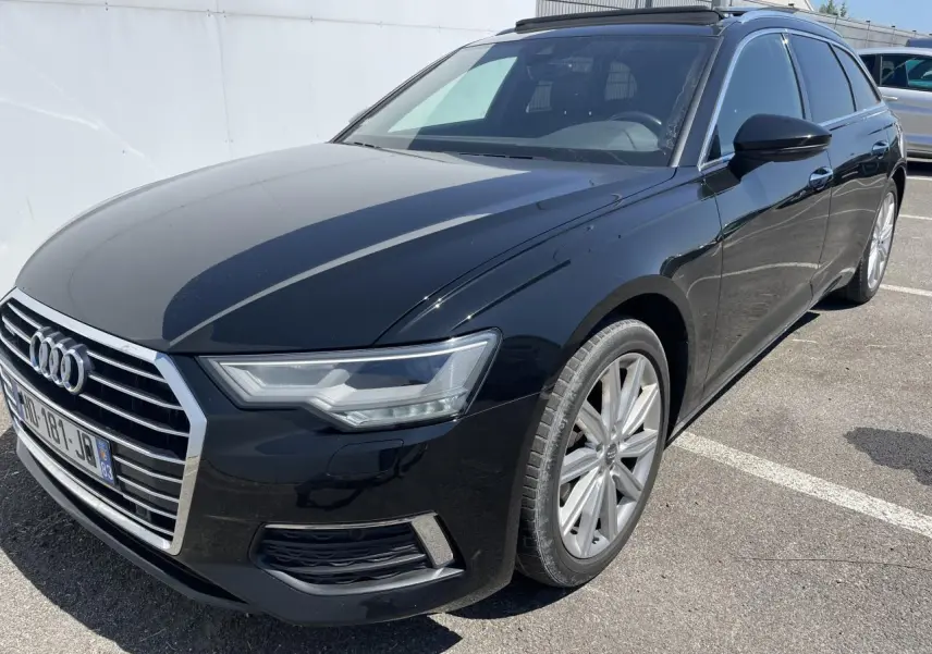 Audi A6 noir métal vue 3/4 avant droit, avec calandre chromée et jantes aluminium 10 branches visibles.