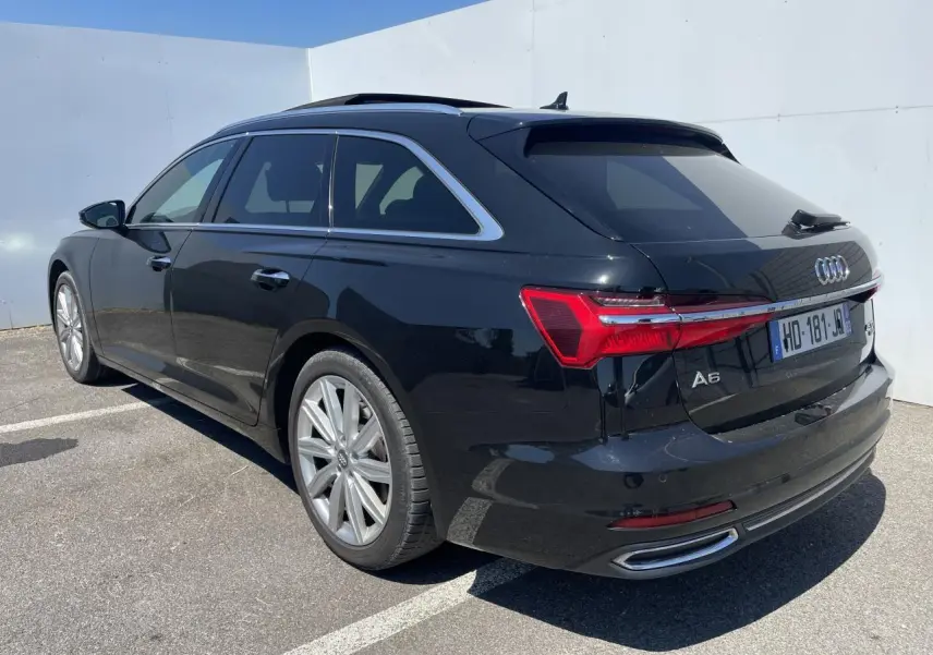 Audi A6 Avant noir métal vue 3/4 arrière droit, jantes 19 pouces et feux arrière LED distinctifs.