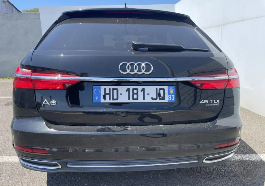 Vue arrière d'une Audi A6 noire métal 45 TDI Quattro avec feux LED et double sortie d'échappement intégrée.