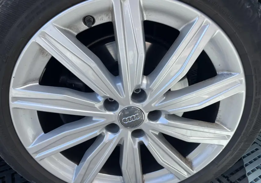Gros plan sur une jante en aluminium 10 branches de couleur argentée d'une Audi A6 noire 2019.
