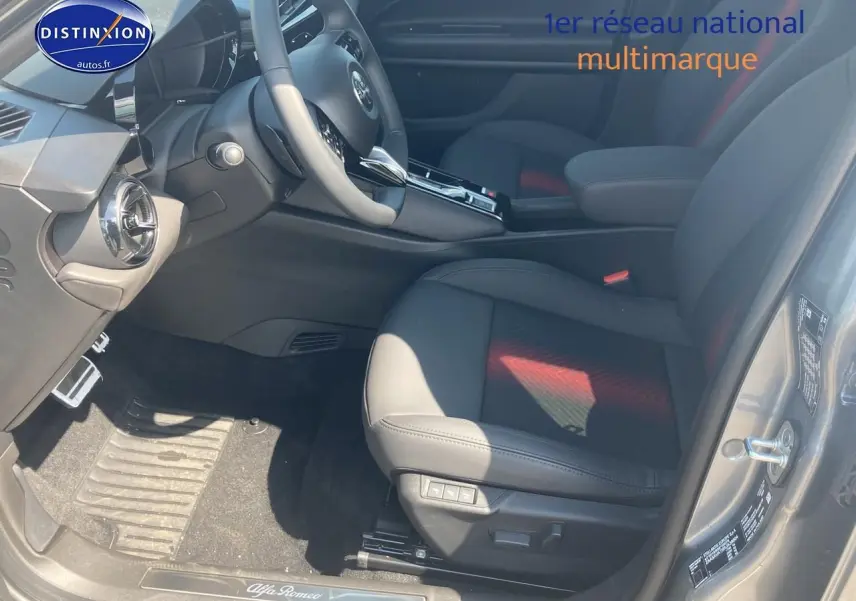 Vue intérieure côté conducteur de l'Alfa Romeo Junior 1.2 hybride 2026 gris t/noir, avec sièges cuir et commandes électriques.