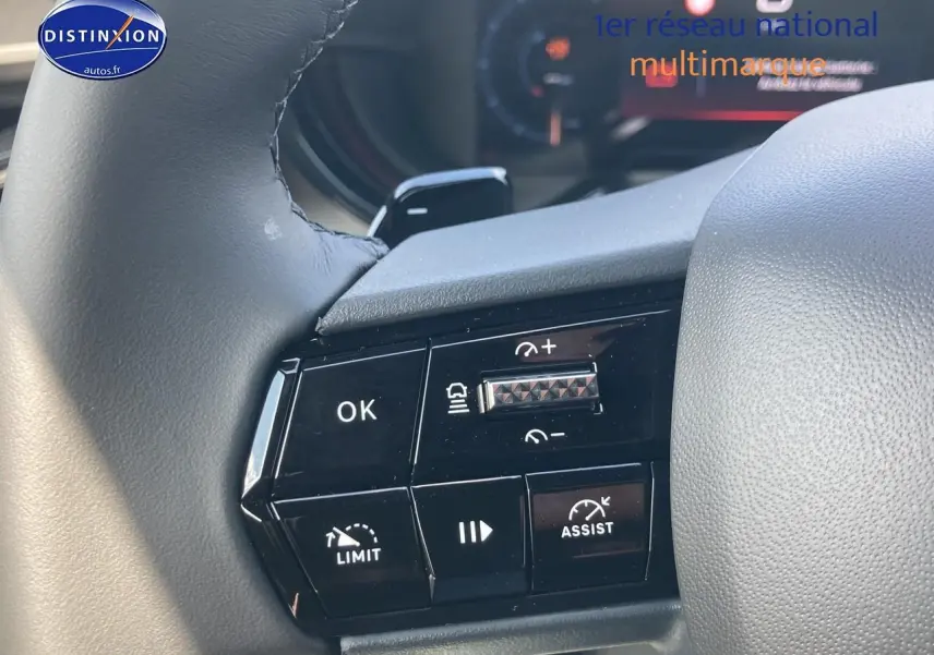 Gros plan sur les commandes au volant de l'Alfa Romeo Junior 1.2 hybride, finition gris t/noir, avec boutons de régulateur et assistance.